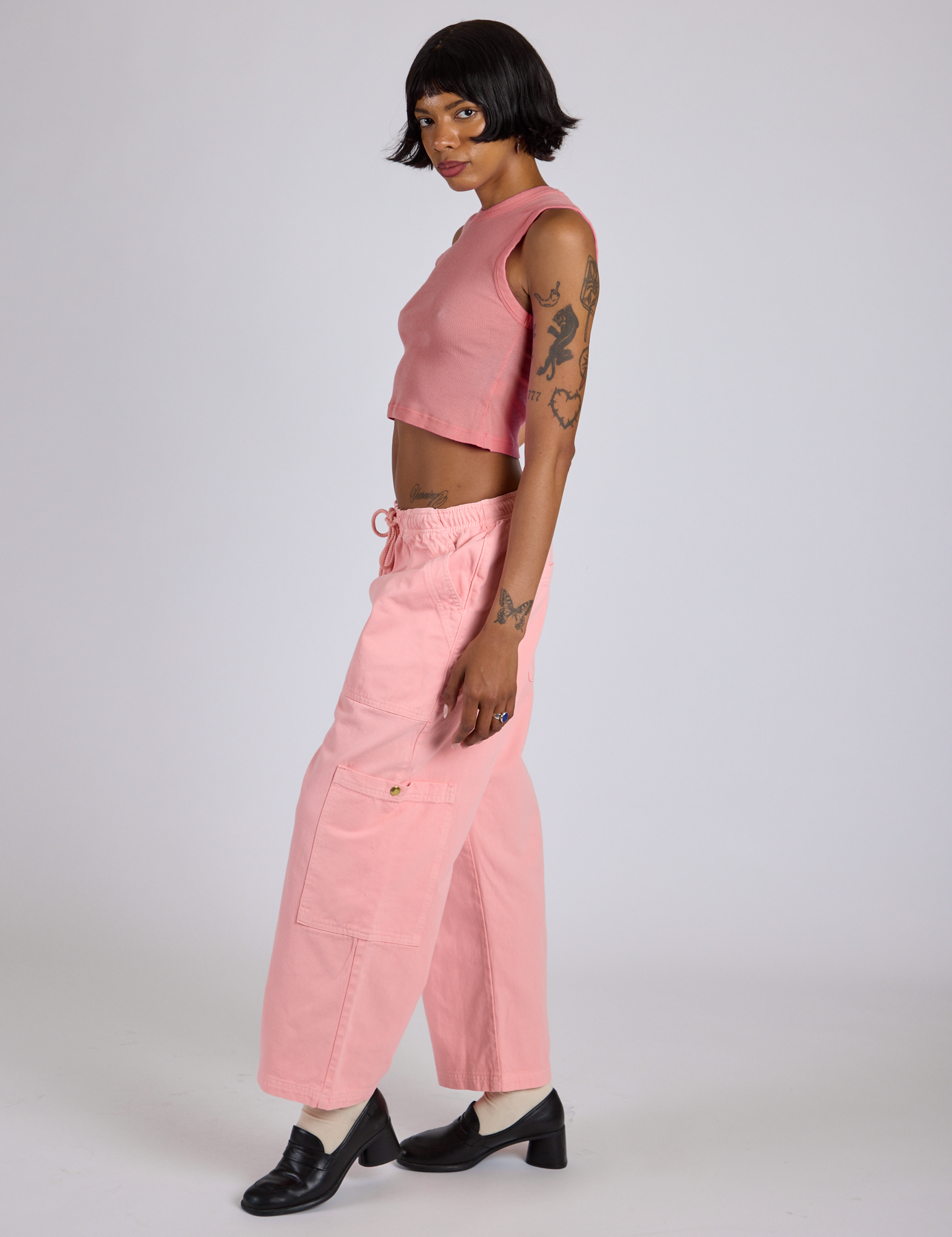 Side view of Drop Pocket Cargo Pants in Baby Pink and matching muscle tee on Kira