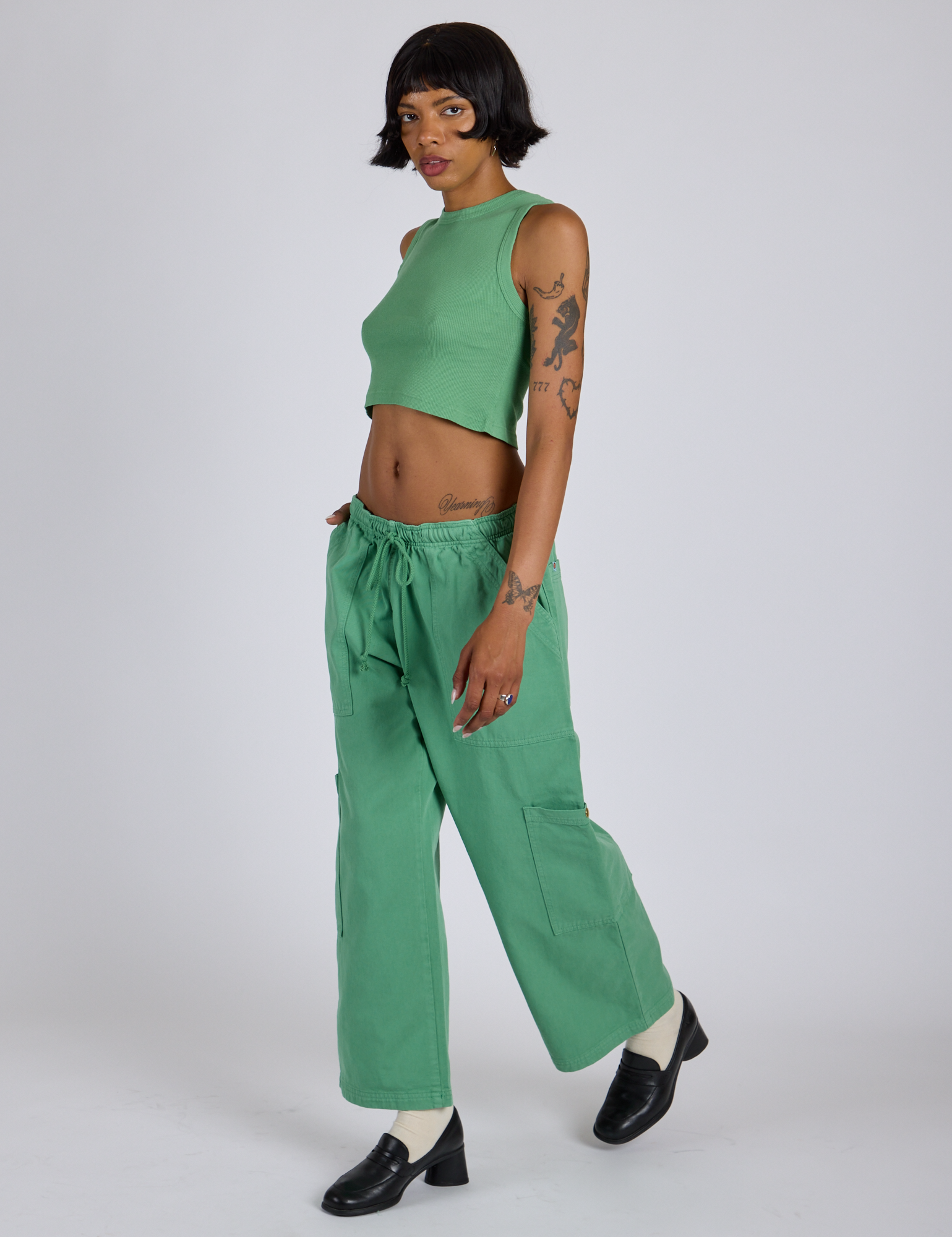 Angled front view of Drop Pocket Cargo Pants in Seafoam Green and matching Muscle Tee on Kira