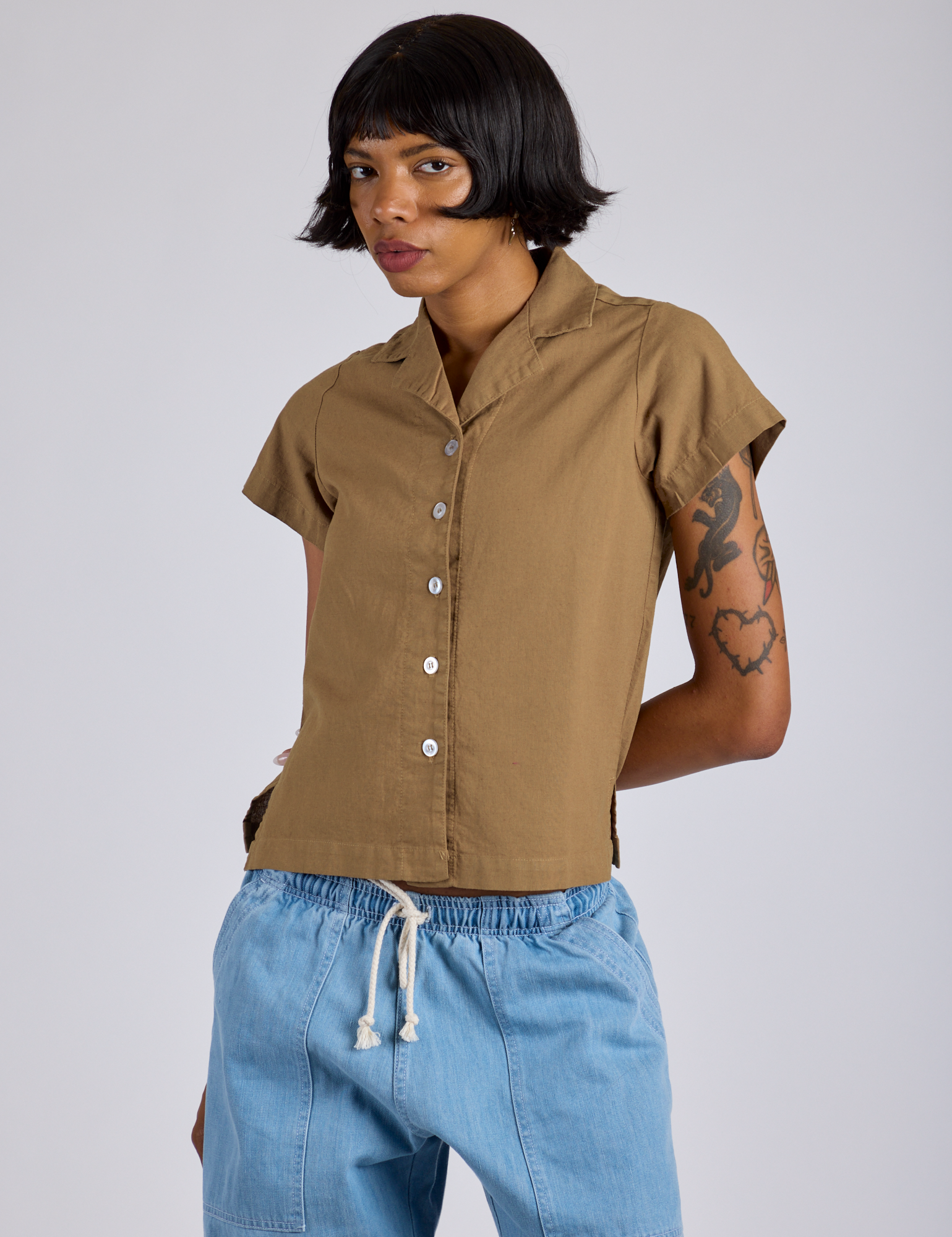 Kira is wearing a buttoned up Pantry Button-Up in Desert Brown