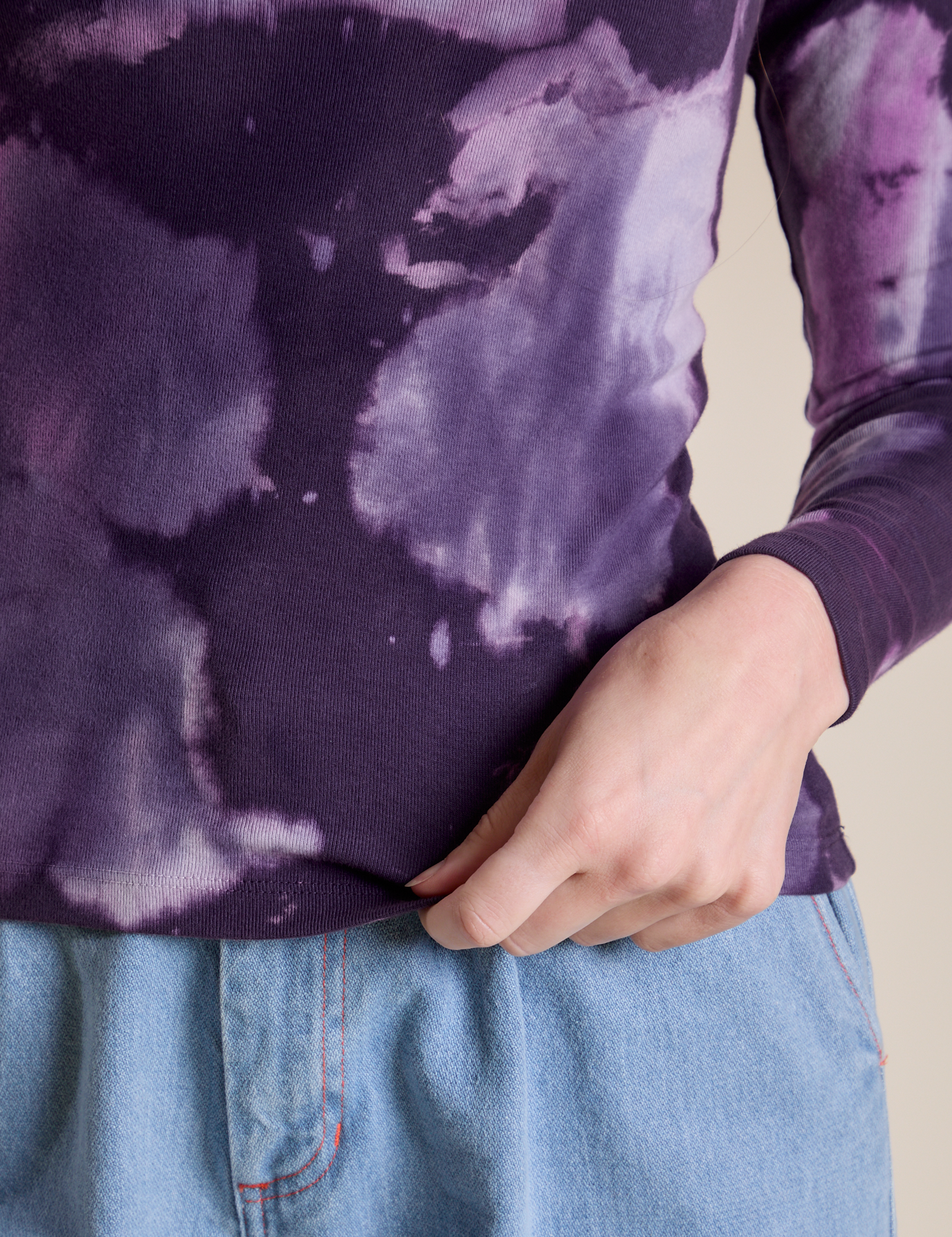 Long Sleeve Baby Tee in Dark Lavender bottom close up with Alex holding the hem