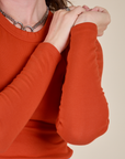 Close up of Long Sleeve Baby Tee in Chili Red sleeves on Alex