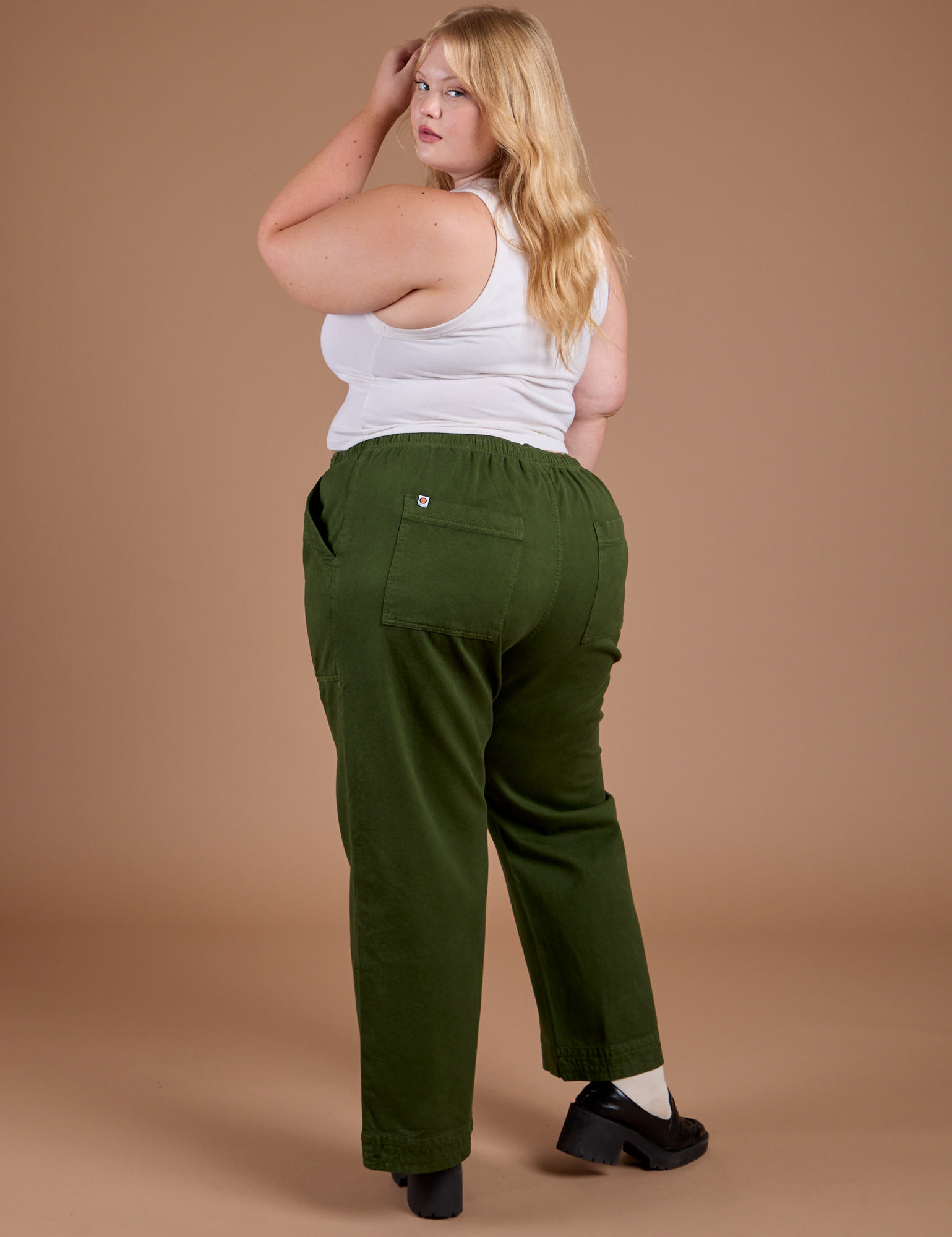Angled back view of Organic Action Pants in Evergreen and vintage tee Cropped Tank on Juliet