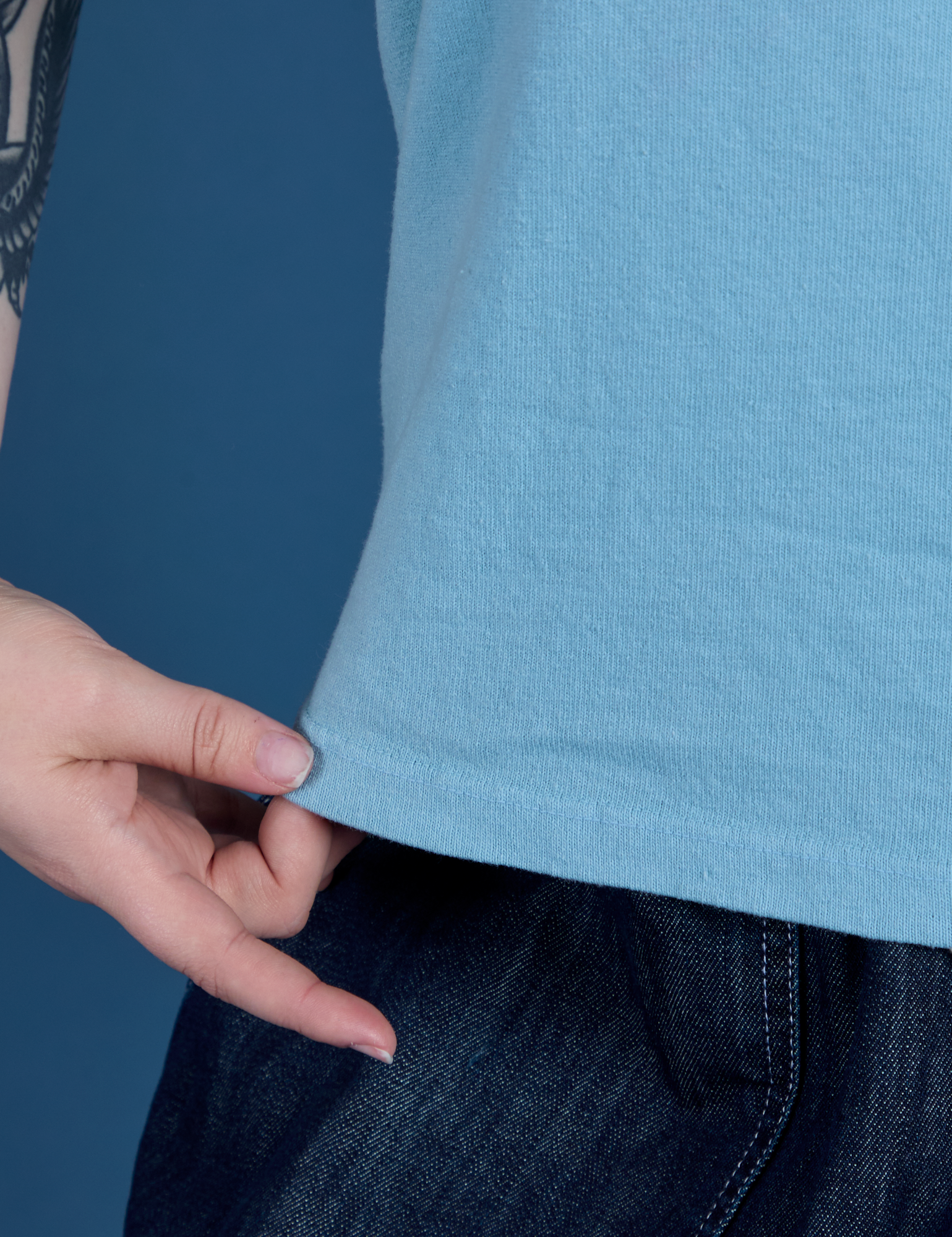 Sydney is holding the hem of Painted Burly Tee in Baby Blue