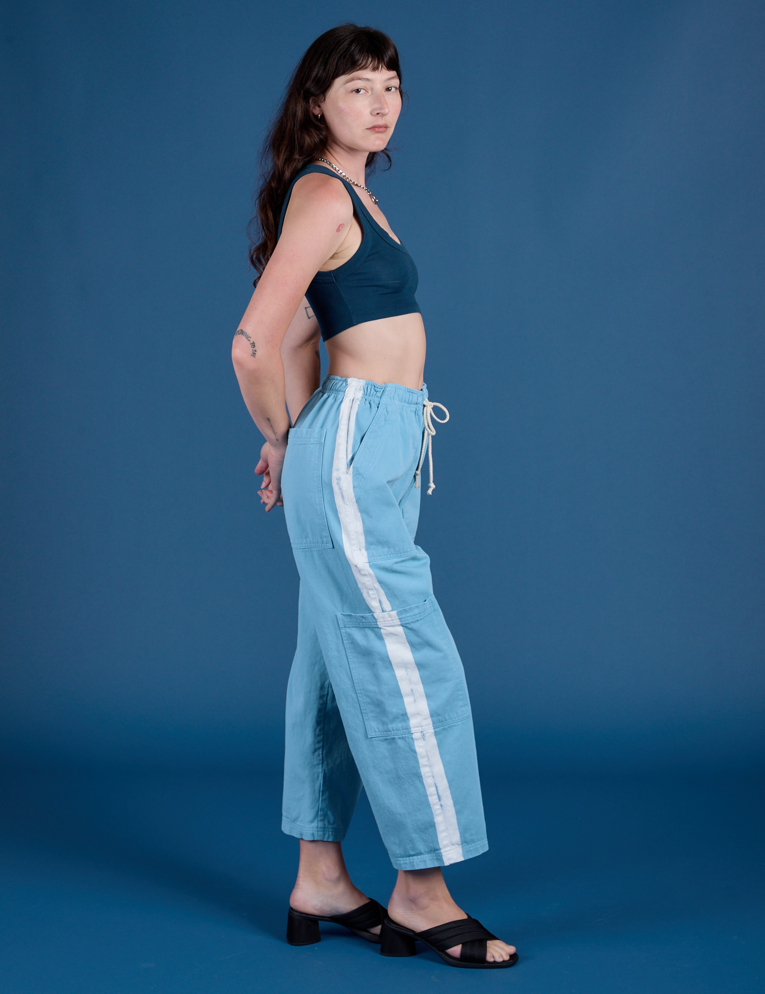 Side view of Painted Drop Pocket Cargo Pants in Baby Blue and lagoon Mini Tank on Alex