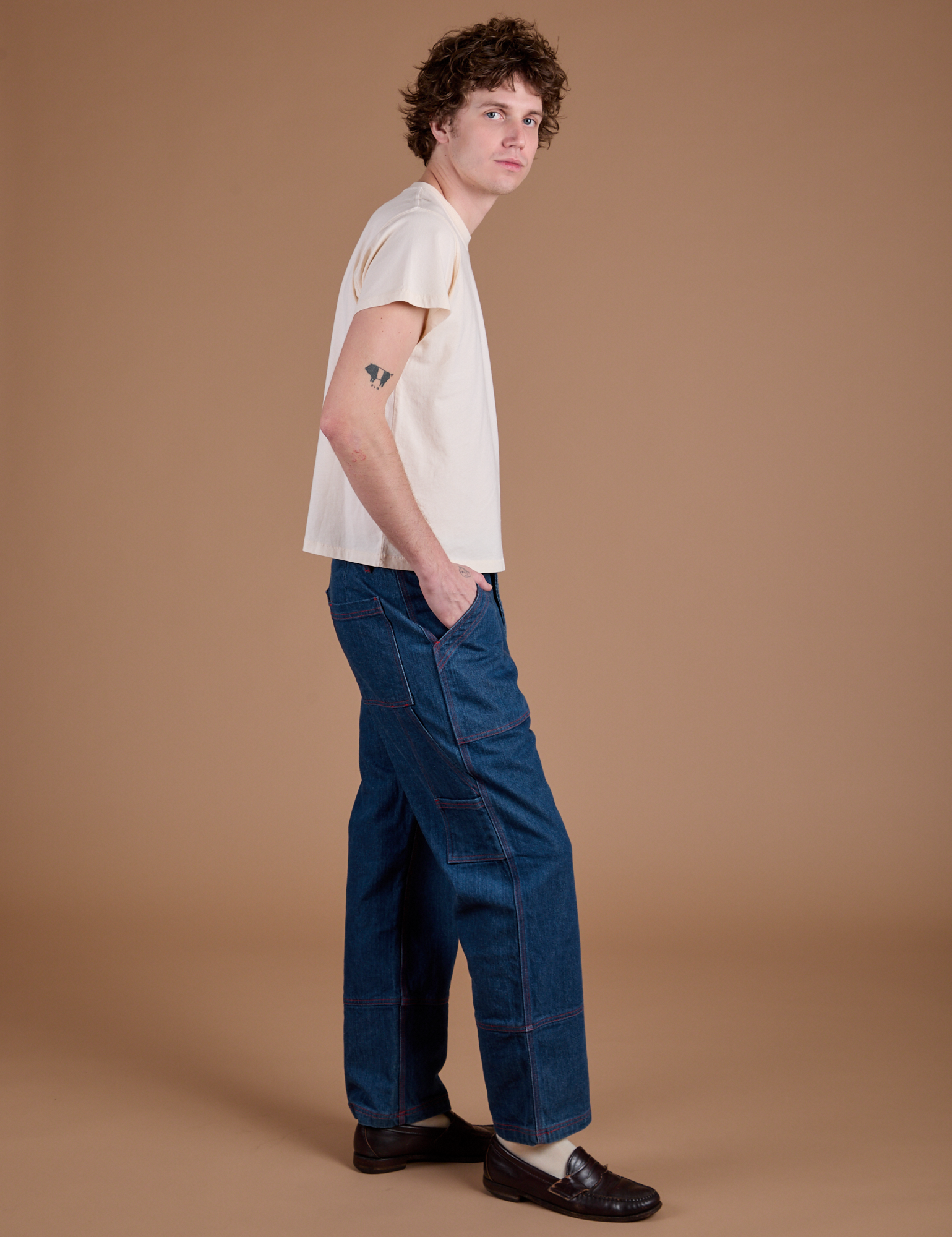 Side view of Carpenter Jeans in Dark Wash and Organic Vintage Tee in Vintage Tee Off-White on Quinn