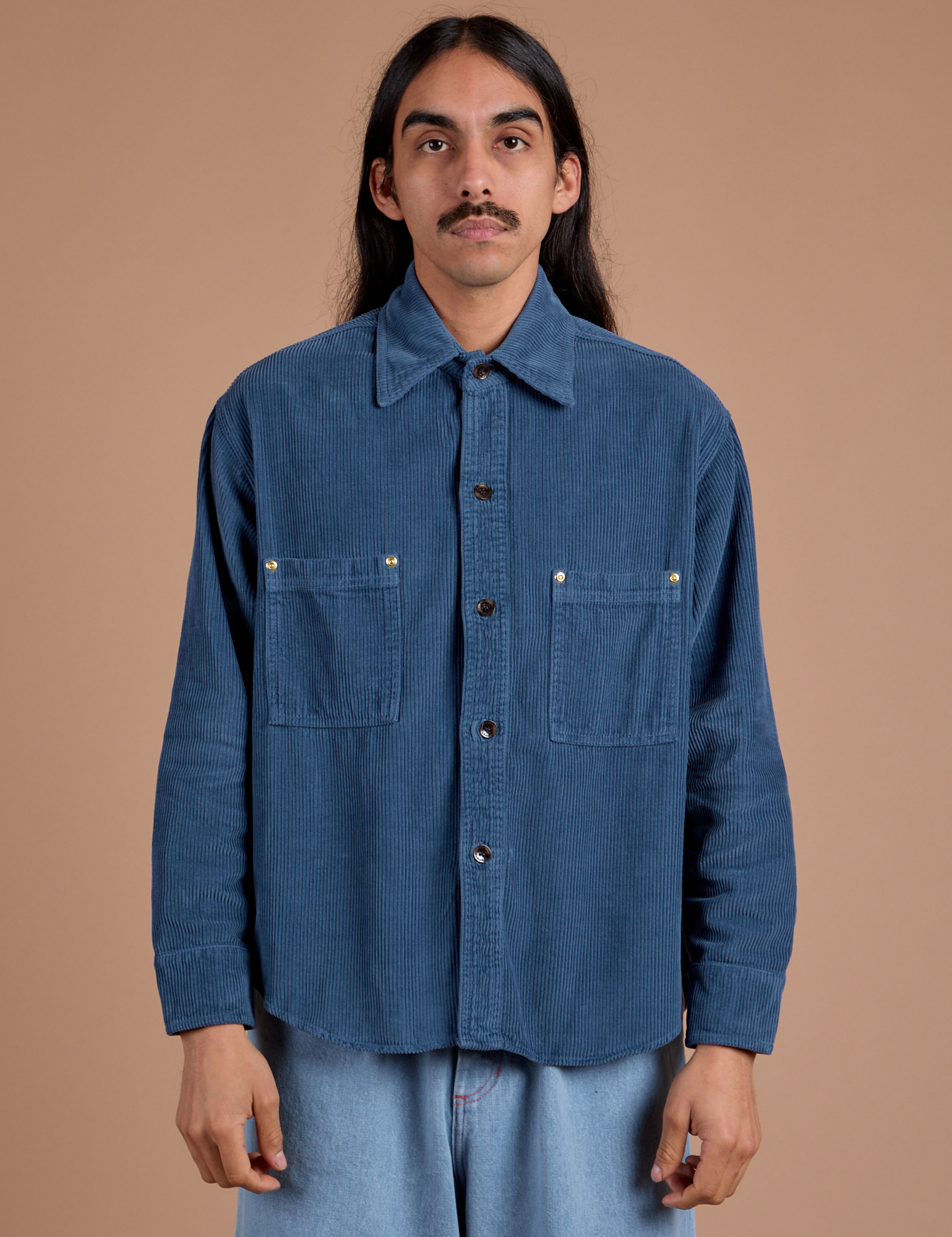 Anthony is wearing a buttoned up Cropped Corduroy Overshirt in French Blue