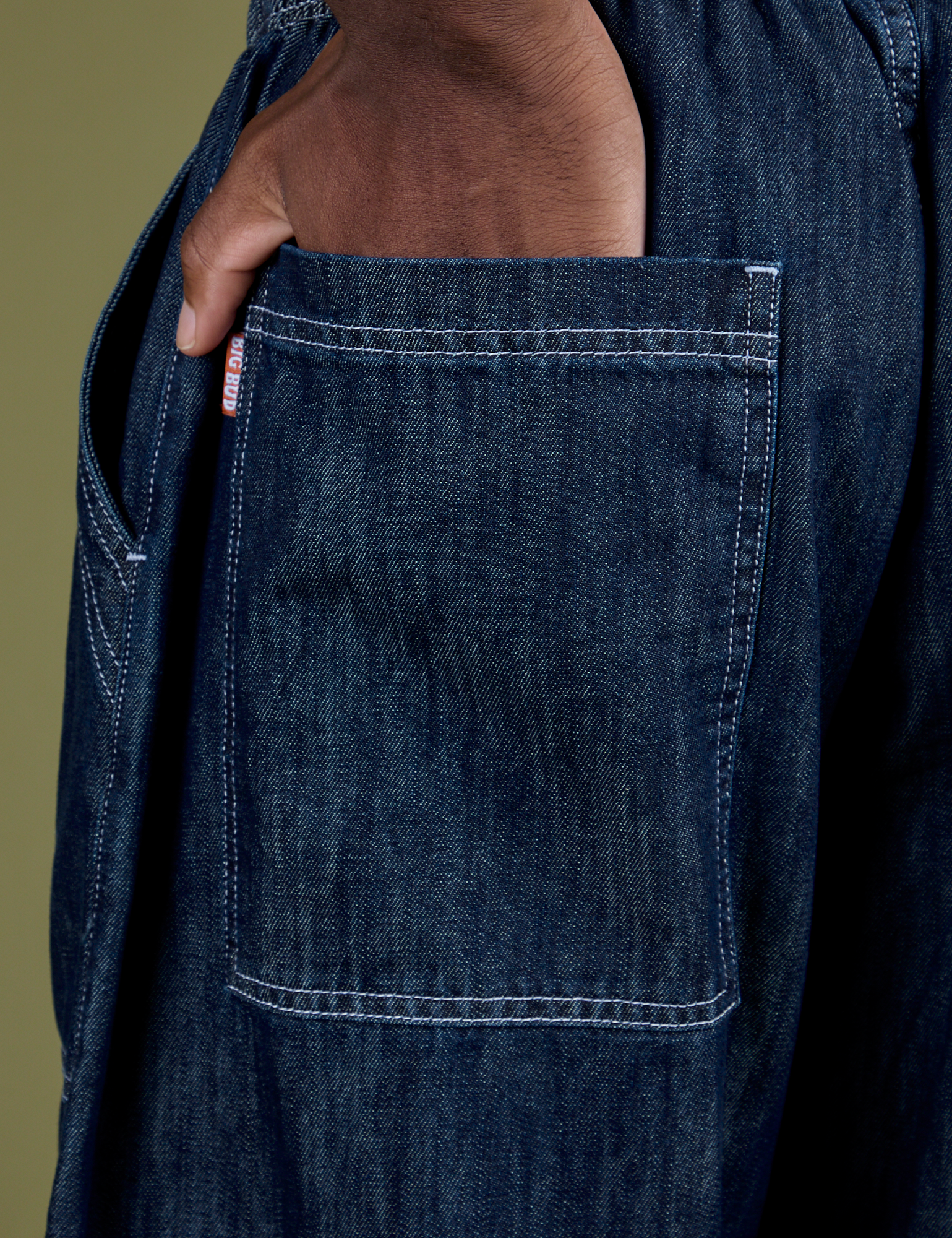 Close up of Isaac's hand in the back pocket of Denim Drop Pocket Pants in Dark Wash