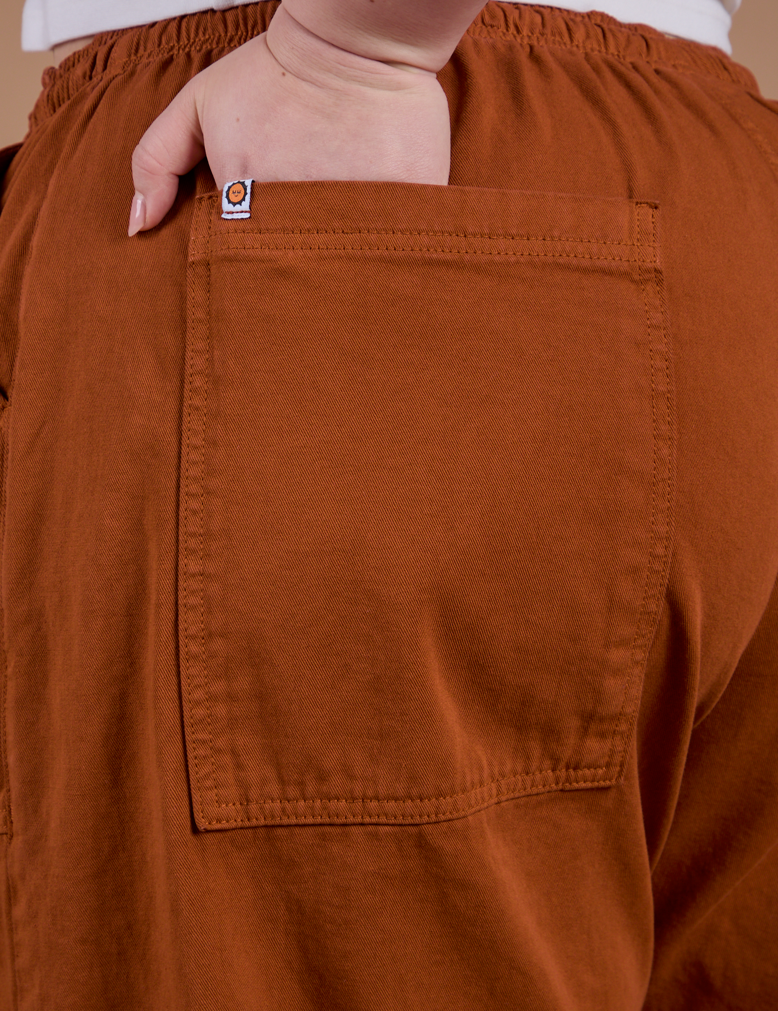 Close up of Ashley's hand in the back pocket of Drop Pocket Cargo Pants in Burnt Terracotta
