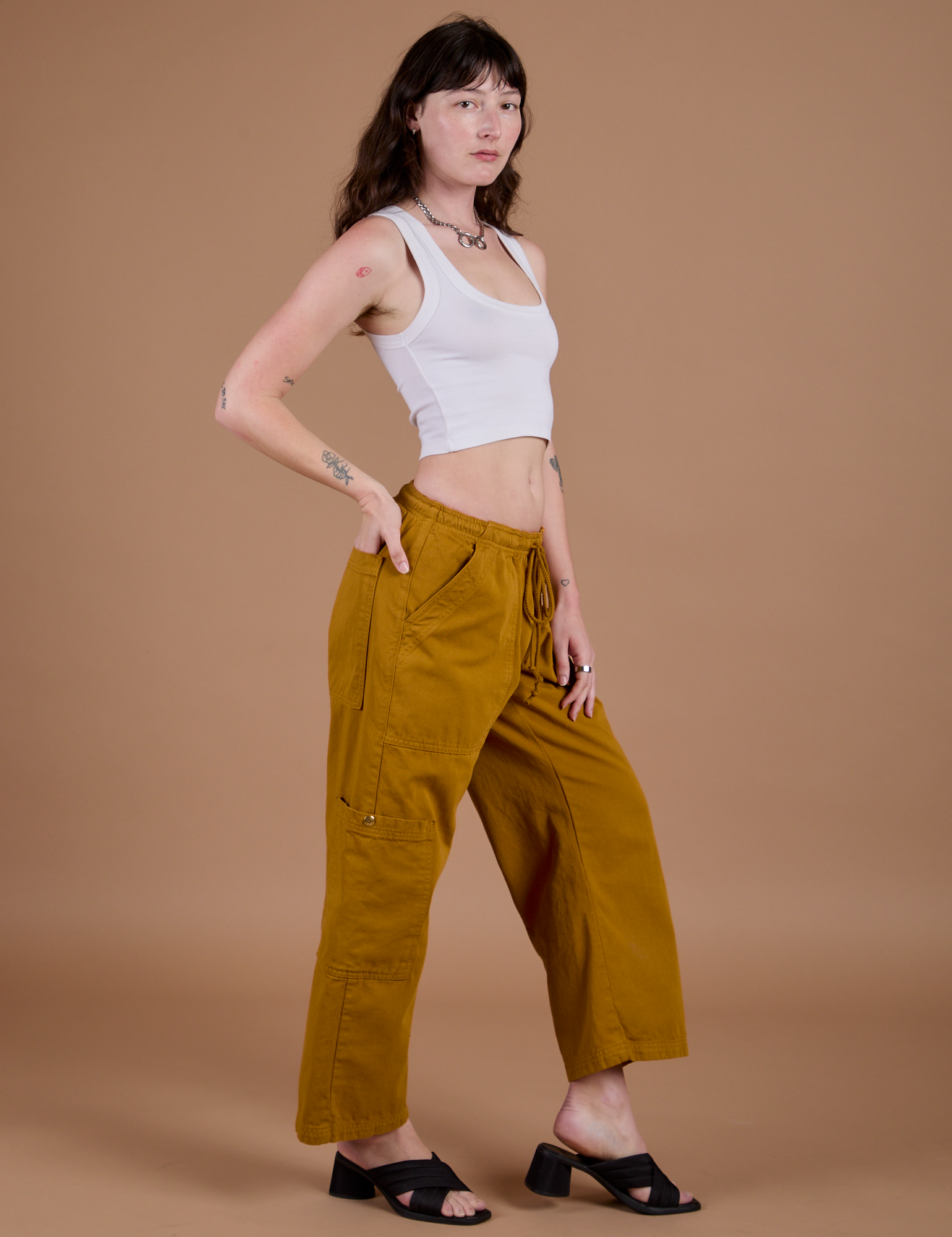 Side view of Drop Pocket Cargo Pants in Spicy Mustard and Cropped Tank in Vintage Tee white on Alex