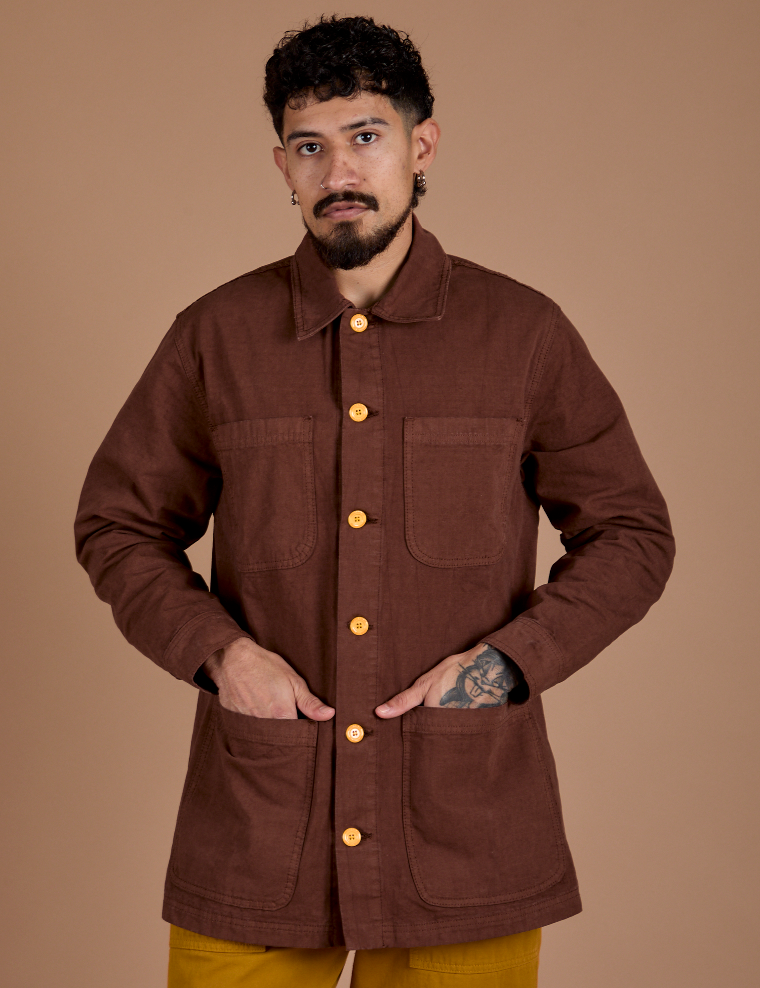 Jesse is wearing a buttoned up Ripstop Field Coat in Fudgesicle Brown