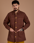 Jesse is wearing a buttoned up Ripstop Field Coat in Fudgesicle Brown