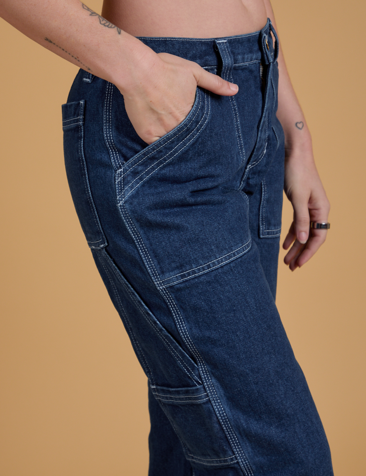 Close up of Alex's hand in the front pocket of Mid-Rise Carpenter Jeans in Dark Wash