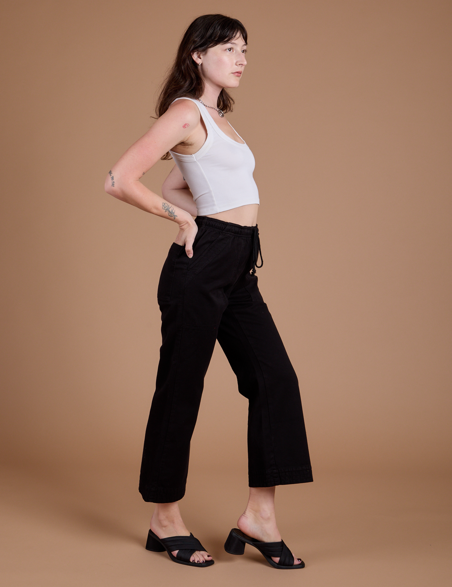 Side view of Organic Action Pants in Basic Black and vintage tee white Cropped Tank on Alex