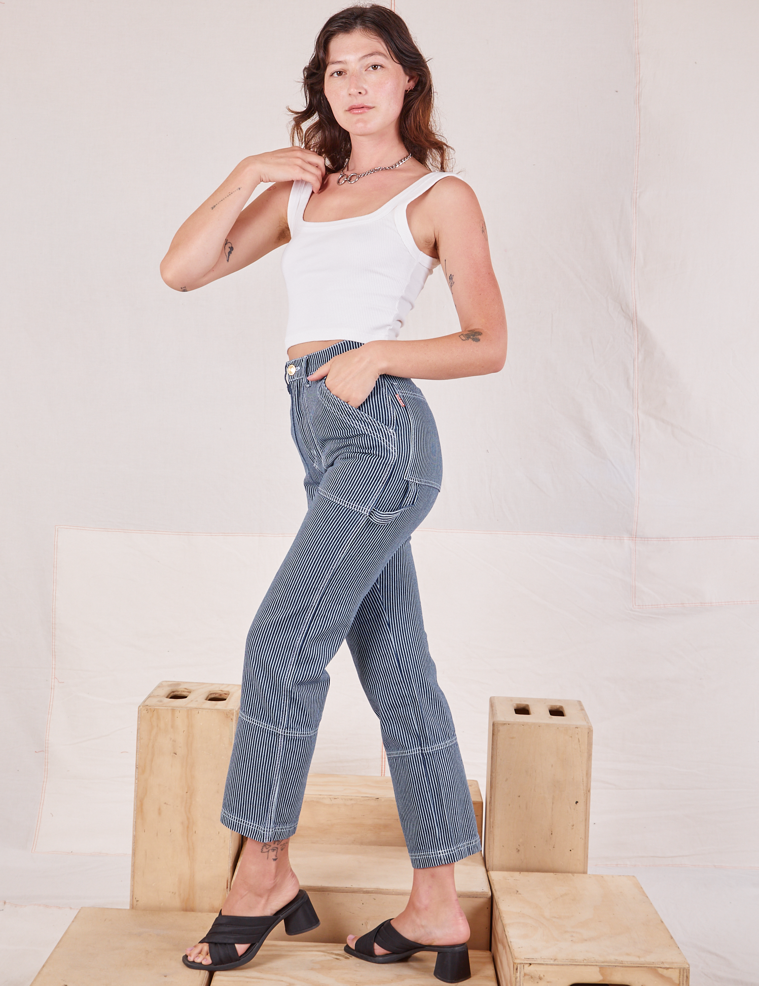 Side view of Carpenter Jeans in Indigo Railroad and vintage tee off-white Square Neck Tank