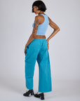 Angled back view of Drop Pocket Cargo Pants in Hawaiian Blue and baby blue Racerback Tank on Kira