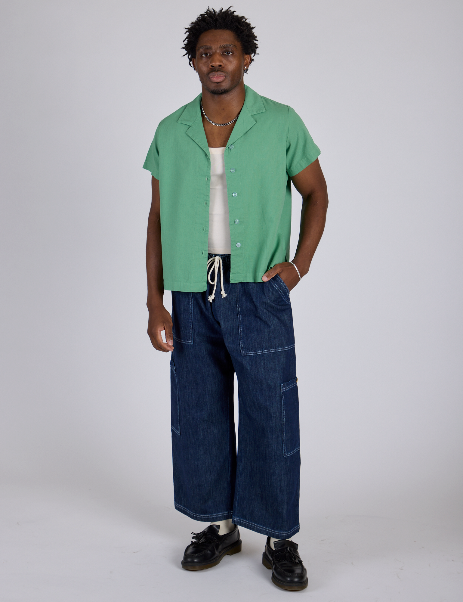 Isaac is wearing Pantry Button-Up in Seafoam Green and dark wash Drop Pocket Pants