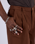 Close up of Jerrod's hand near the front pocket of Pleated Trouser Shorts in Fudgesicle Brown