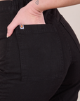 Close up of Alex's hand in the back pocket of Western Pants in Basic Black