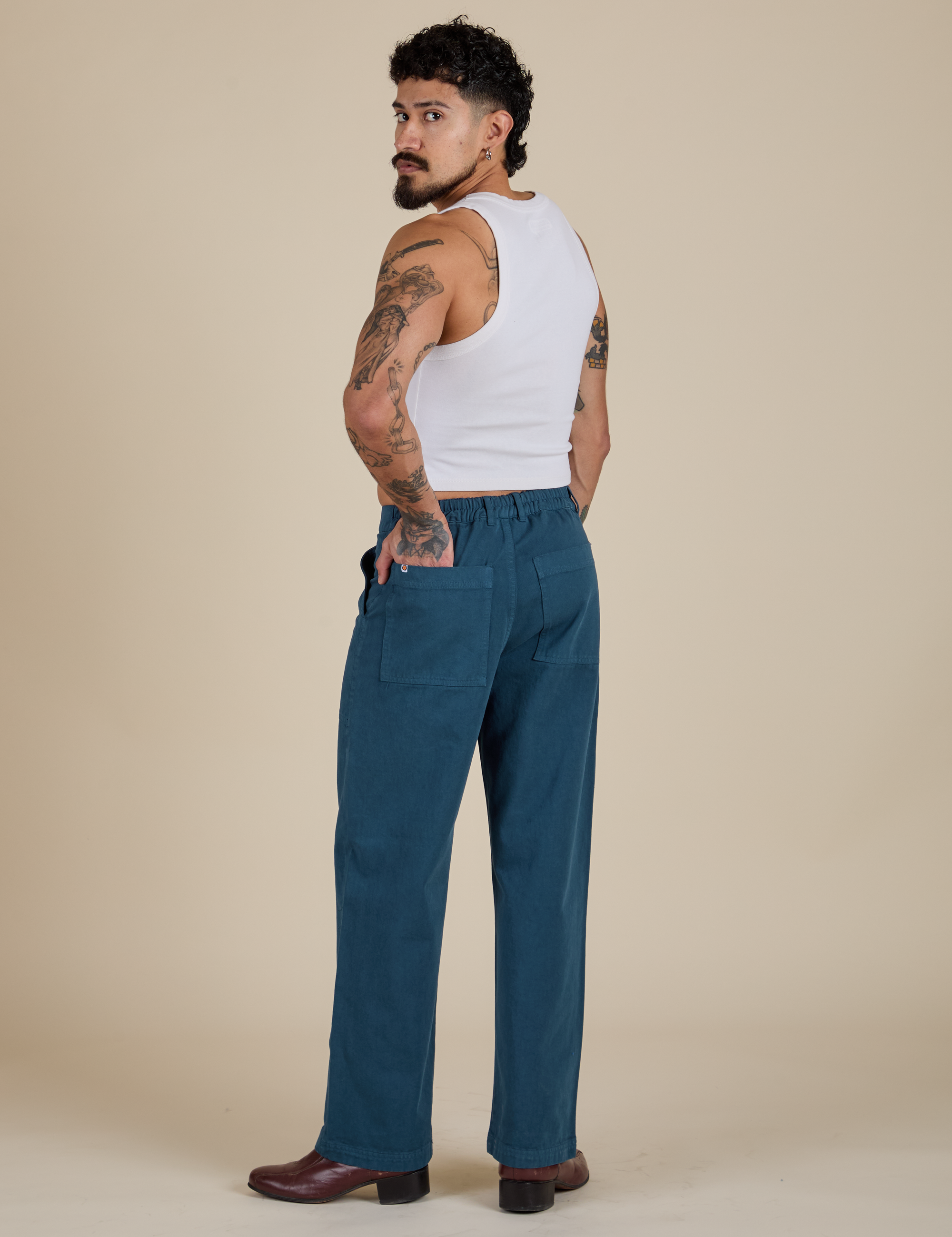 Angled back view of Work Pants in Lagoon and vintage tee white Cropped Tank on Jesse