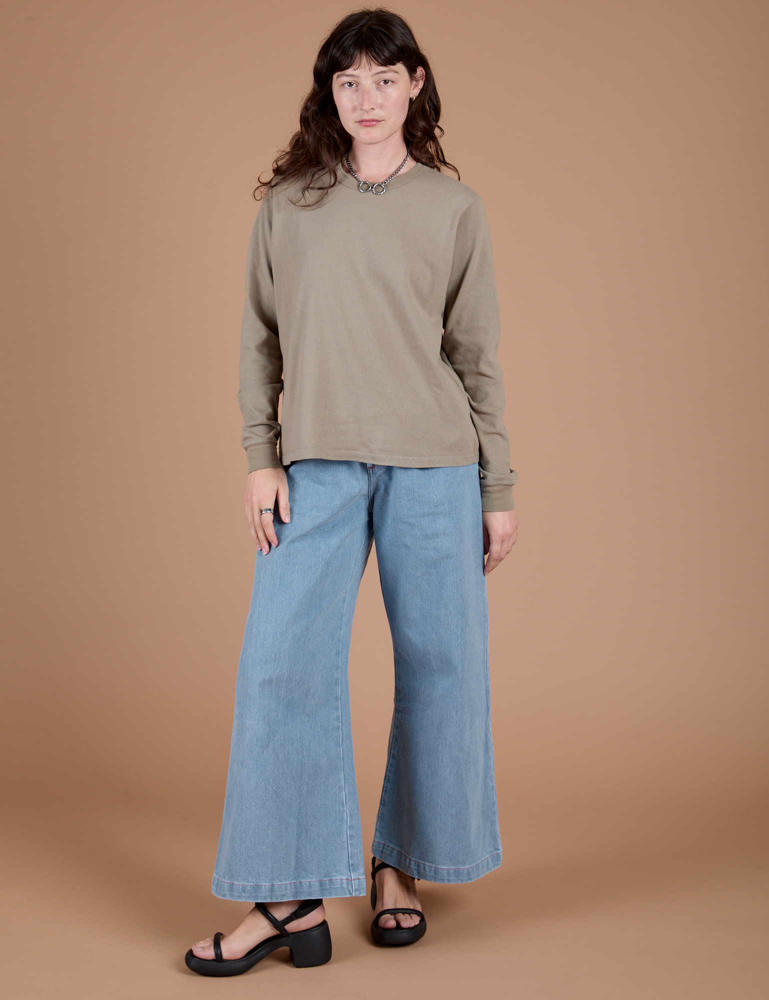 Alex is wearing Long Sleeve Burly Tee in Khaki Grey and light wash Indigo Wide Leg Trousers