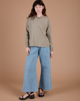 Alex is wearing Long Sleeve Burly Tee in Khaki Grey and light wash Indigo Wide Leg Trousers