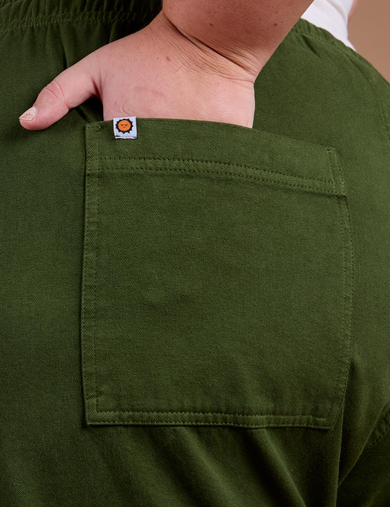 Close up of Juliet's hand in the back pocket of Organic Action Pants in Evergreen