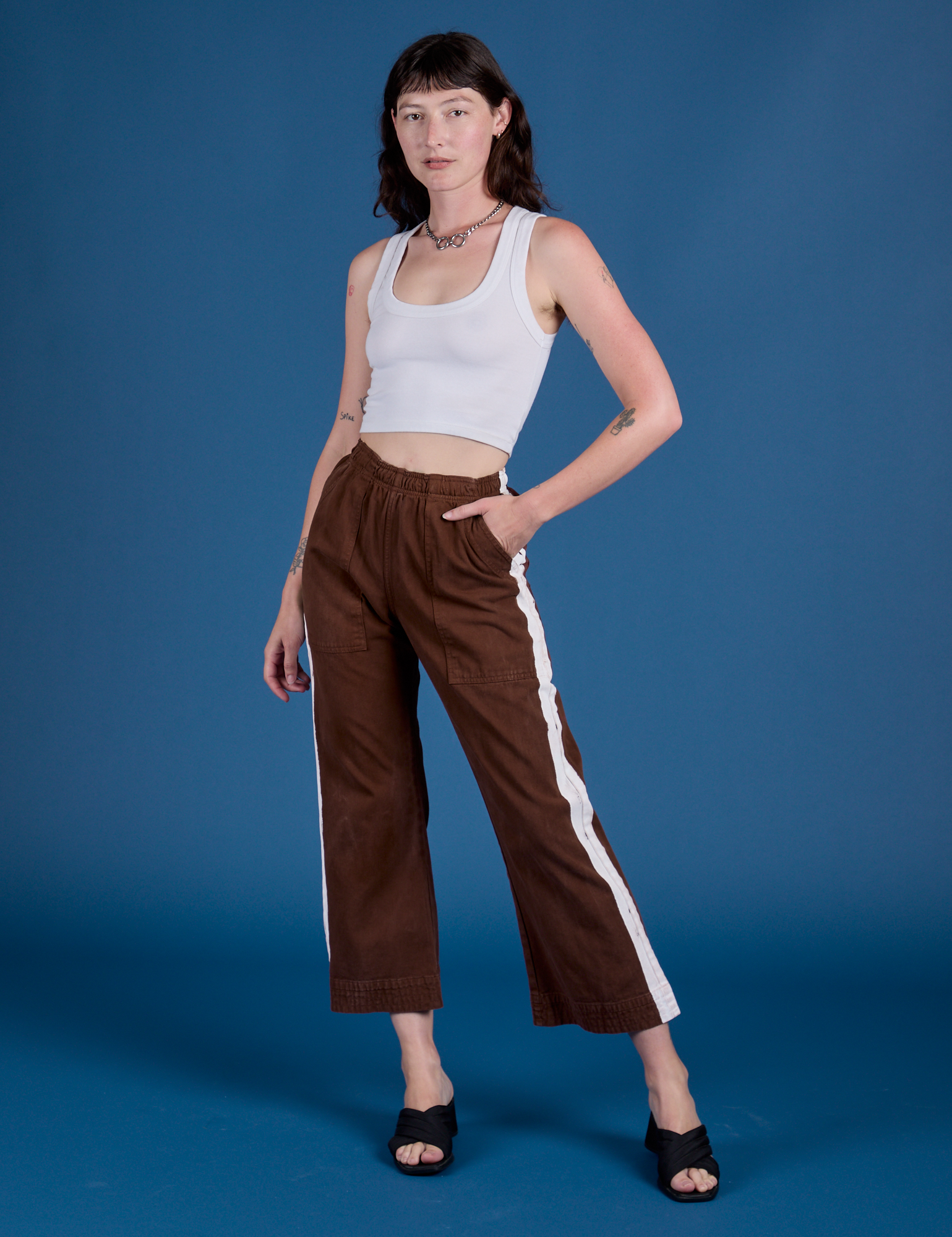 Alex is 5’8” and wearing XXS Painted Action Pants in Fudgesicle Brown paired with vintage tee white Cropped Tank