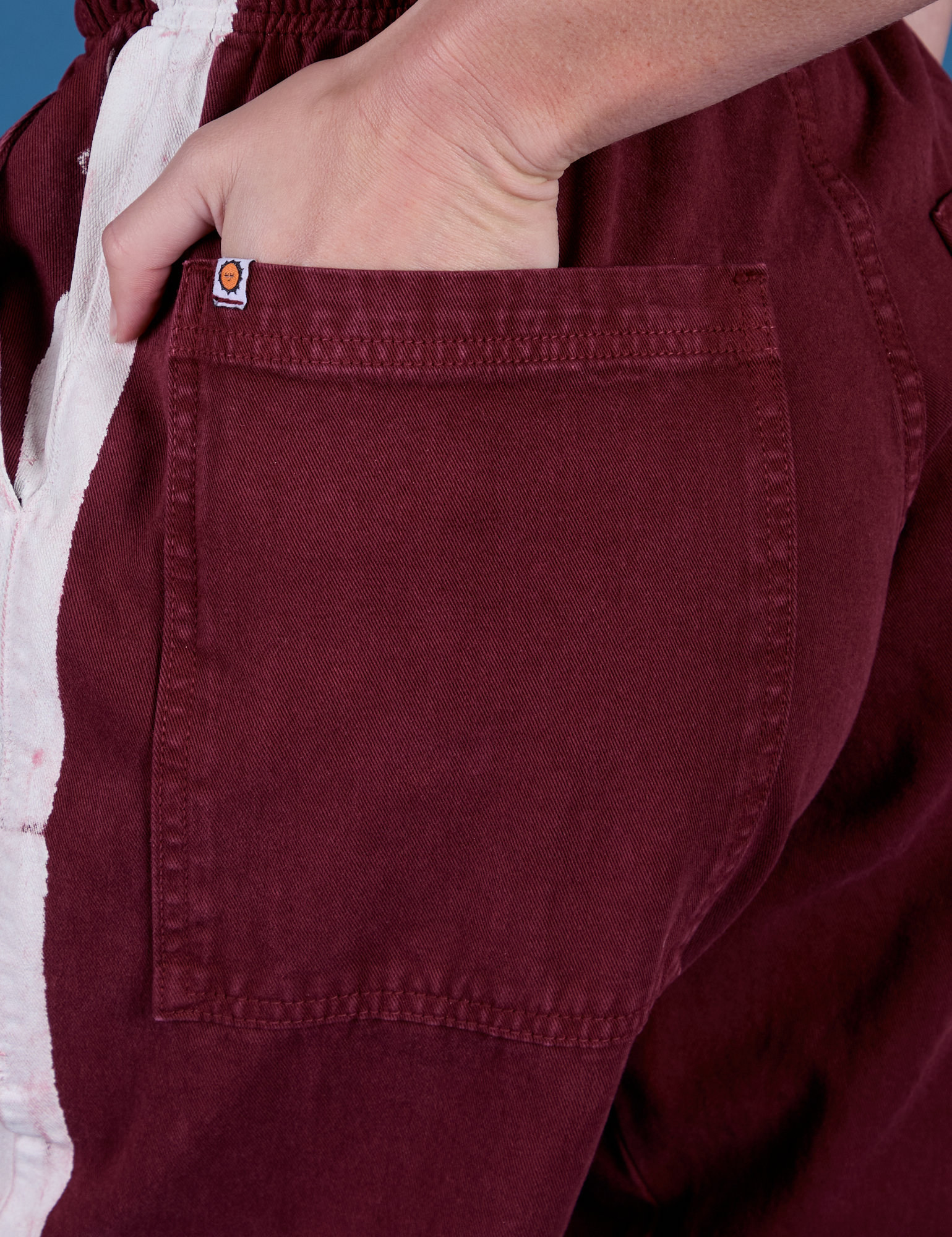 Close up of Alex's hand in the back pocket of Painted Drop Pocket Cargo Pants in Red Wine