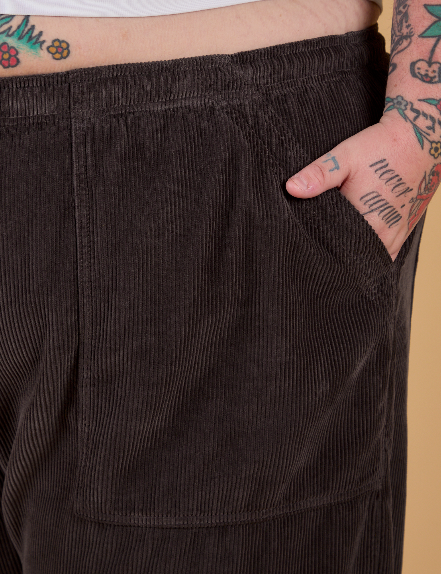 Close up of Sam's hand in the front pocket of Corduroy Drop Pocket Cargo Pants in Espresso Brown