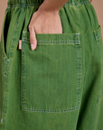 Close up of Anjaline's hand in the back pocket of Denim Drop Pocket Pants in Green Overdye