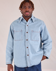 Issac is wearing a buttoned up Denim Overshirt in Light Wash