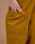 Drop Pocket Cargo Pants in Spicy Mustard pant leg pocket close up with Alex's hand tucked in