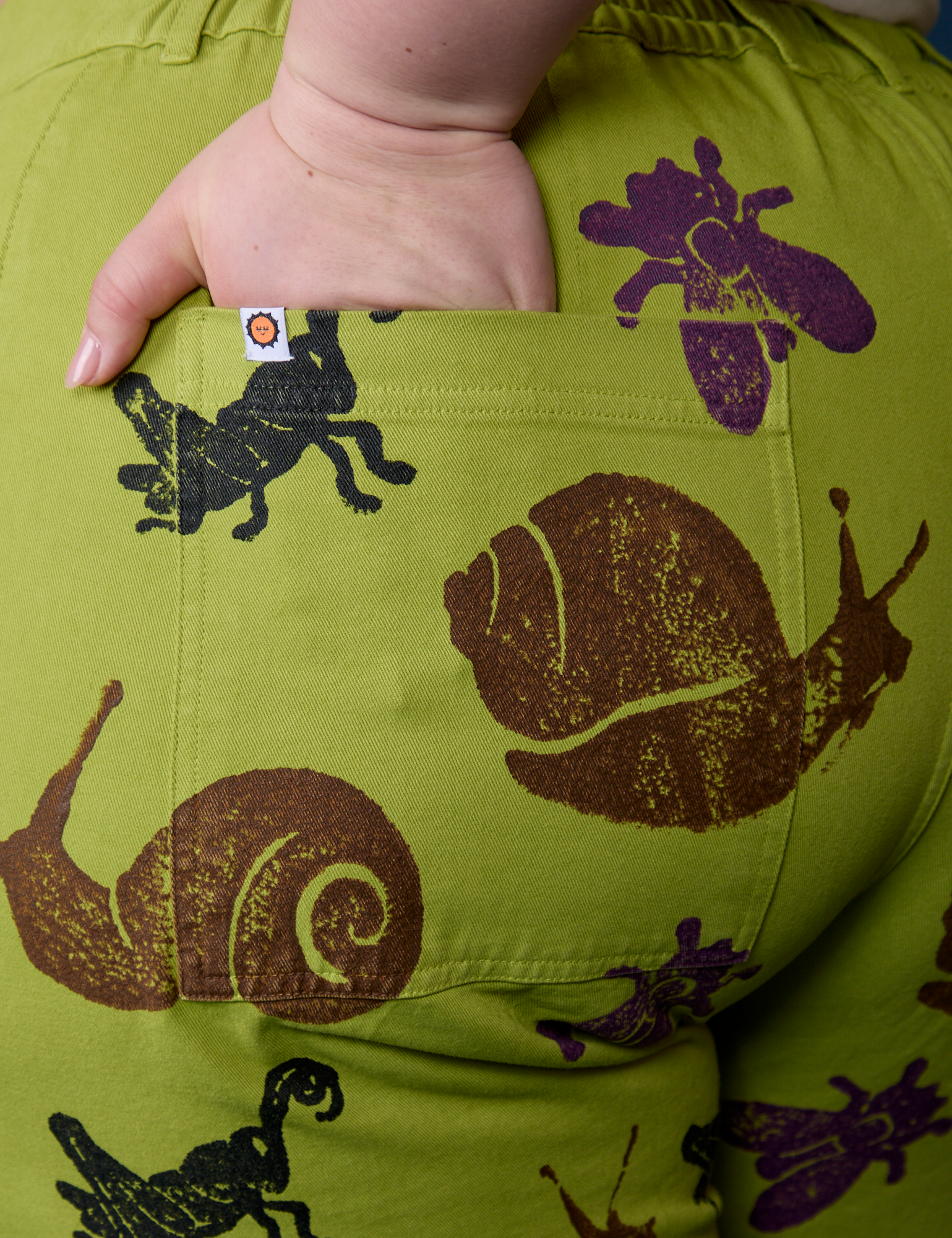 Close up of Ashley's hand in the back pocket of Paintstamped Work Pants in Froggy