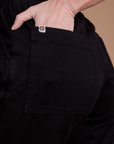 Close up of Alex's hand in the back pocket of Organic Action Pants in Basic Black