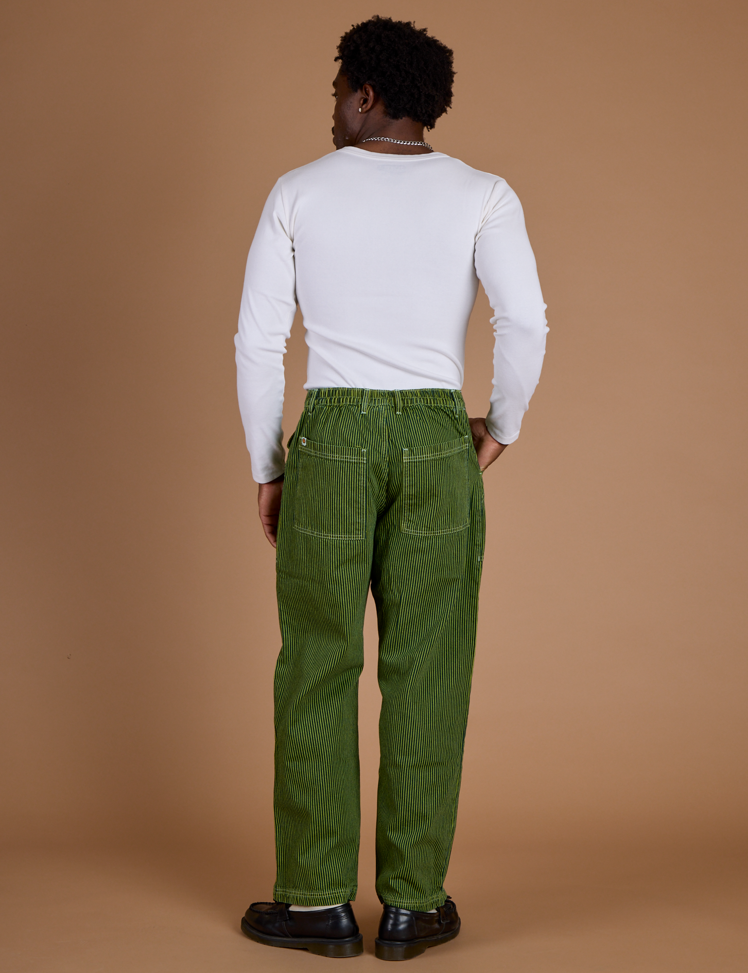 Back view of Railroad Denim Work Pants in Gross Green Overdye and vintage tee white long sleeve baby tee