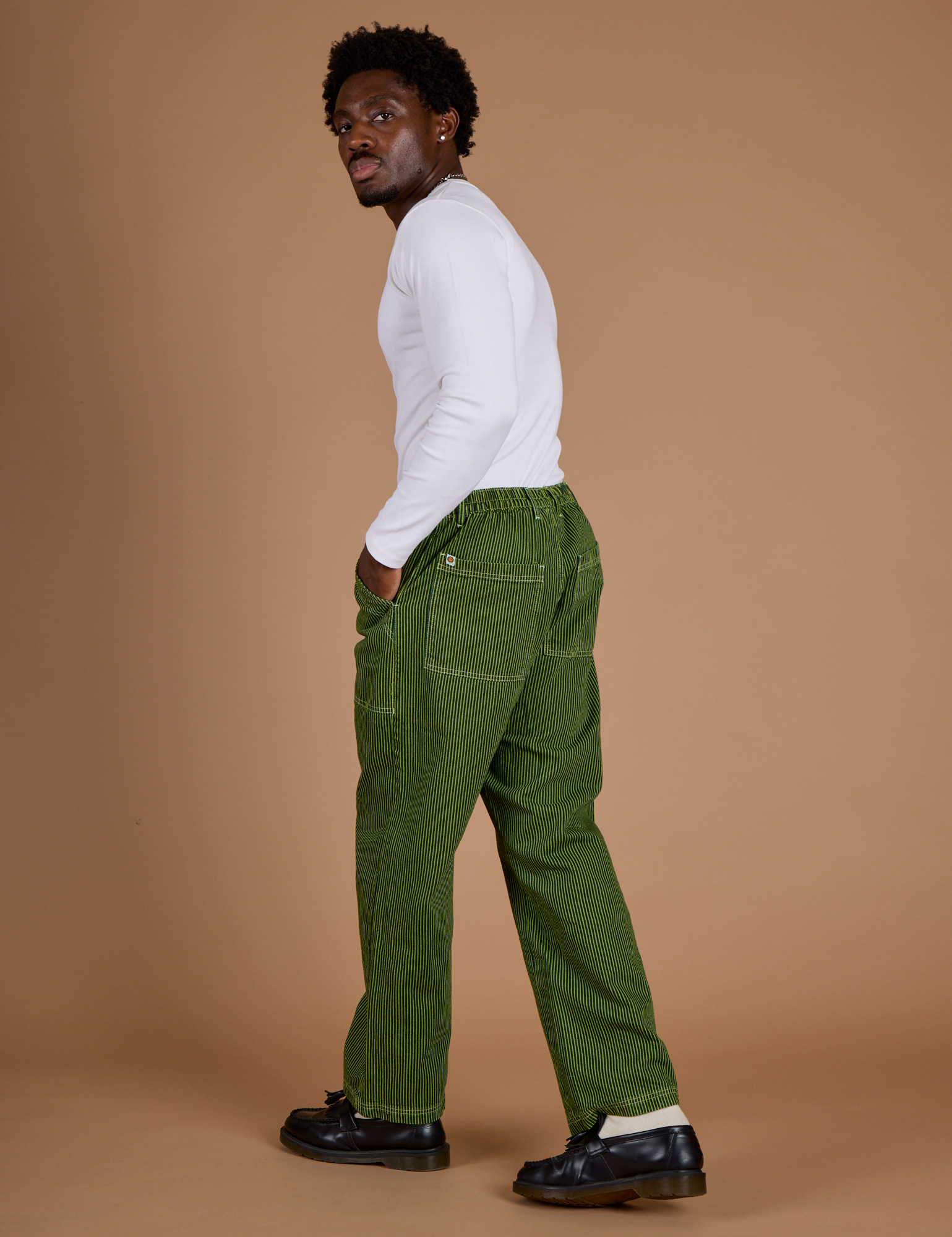 Angled back view of Railroad Denim Work Pants in Gross Green Overdye and vintage tee white long sleeve baby tee