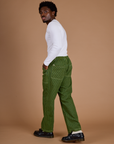 Angled back view of Railroad Denim Work Pants in Gross Green Overdye and vintage tee white long sleeve baby tee