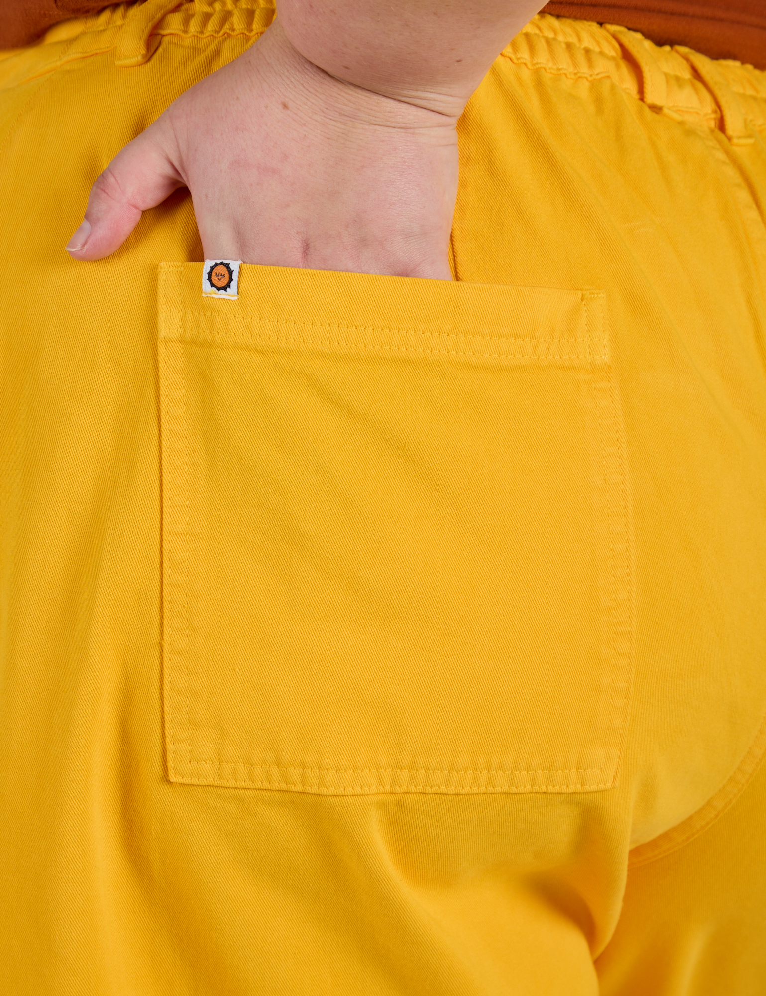 Close up of Juliet's hand in the back pocket of Longline Work Shorts in Sunshine Yellow