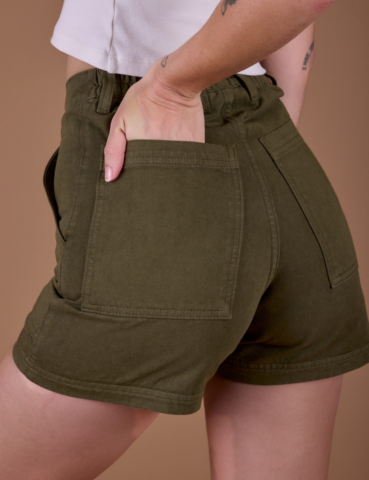 Close up of Alex's hand in the back pocket of Classic Work Shorts in Surplus Green