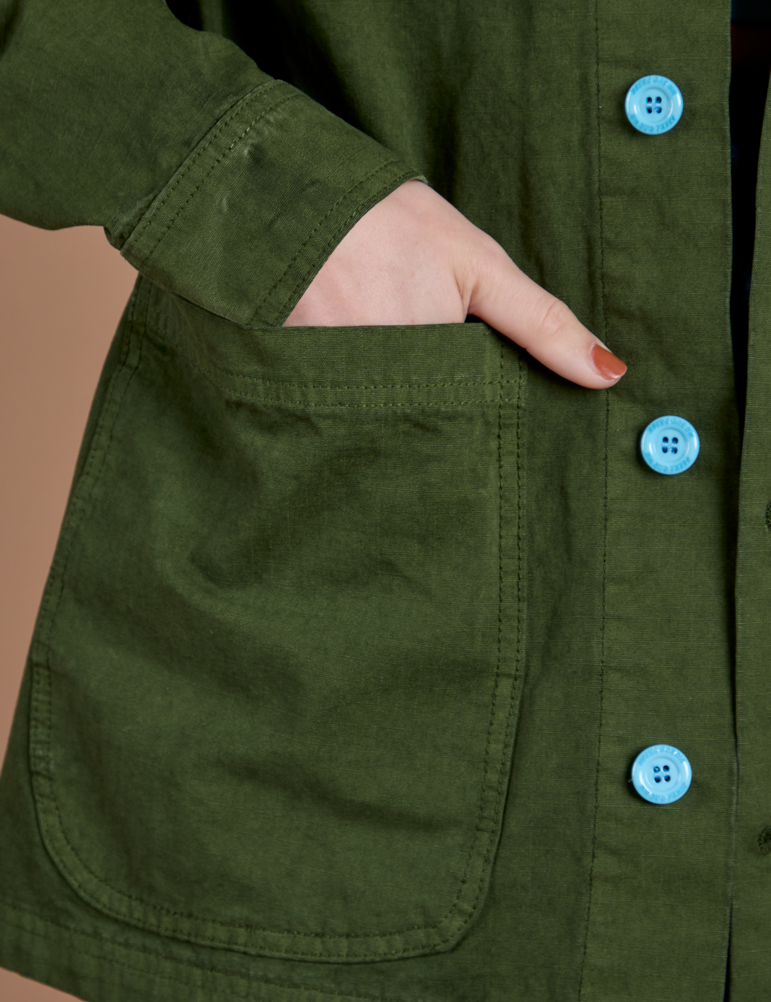 Close up of Alex's hand in the front pocket of Ripstop Field Coat in Evergreen
