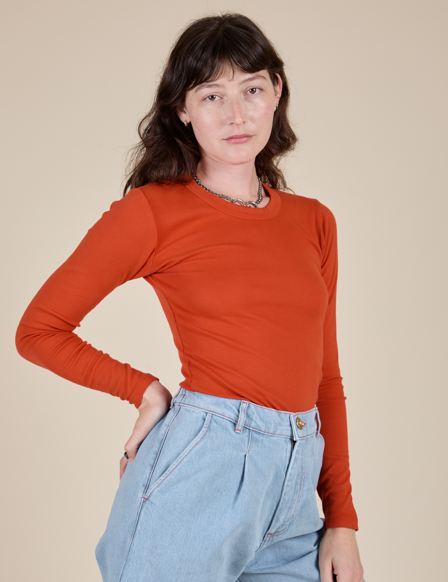 Angled front view of Long Sleeve Baby Tee in Chili Red on Alex