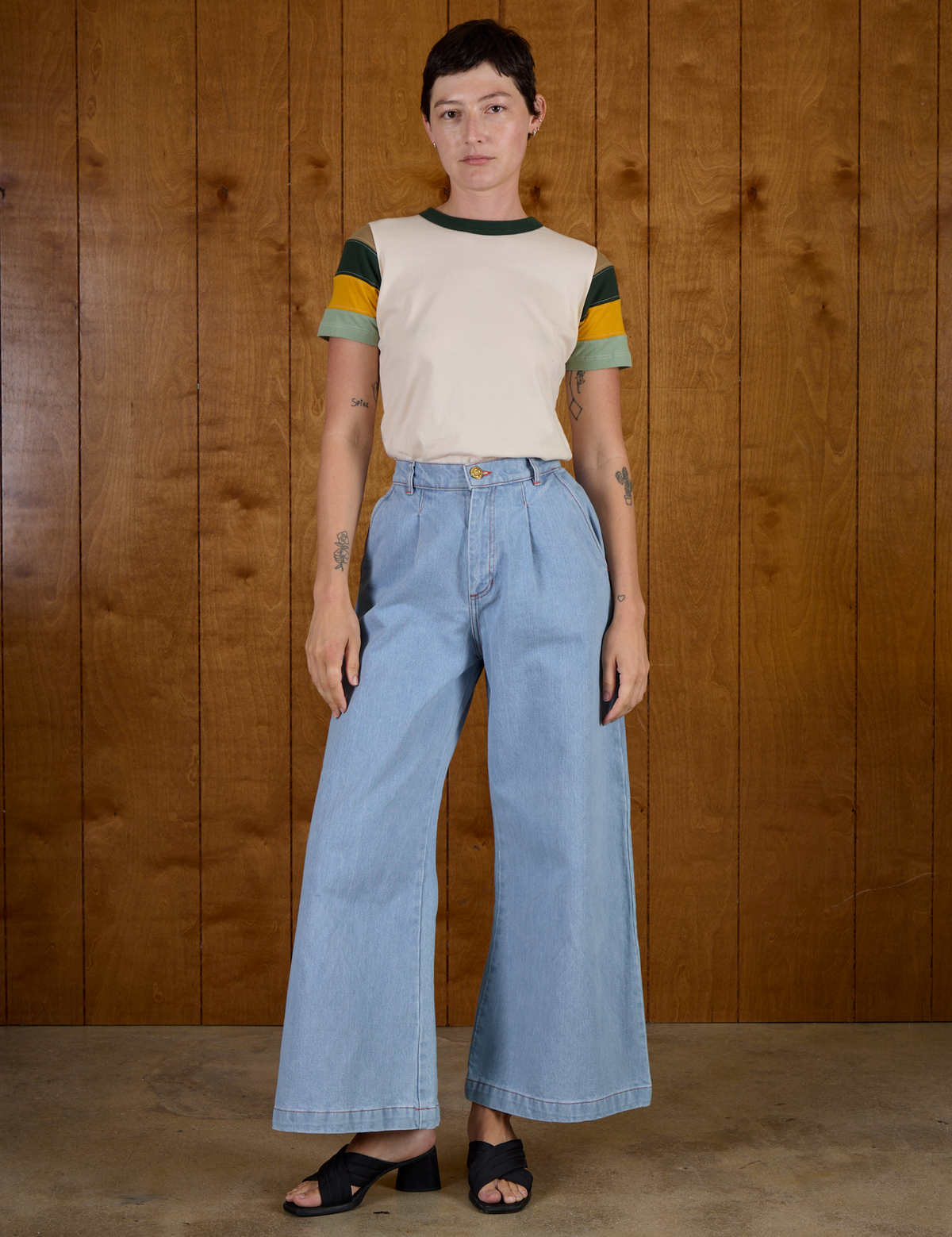 Alex is wearing Calypso Tee in Off White Multi tucked into light wash Denim Wide Leg Trousers