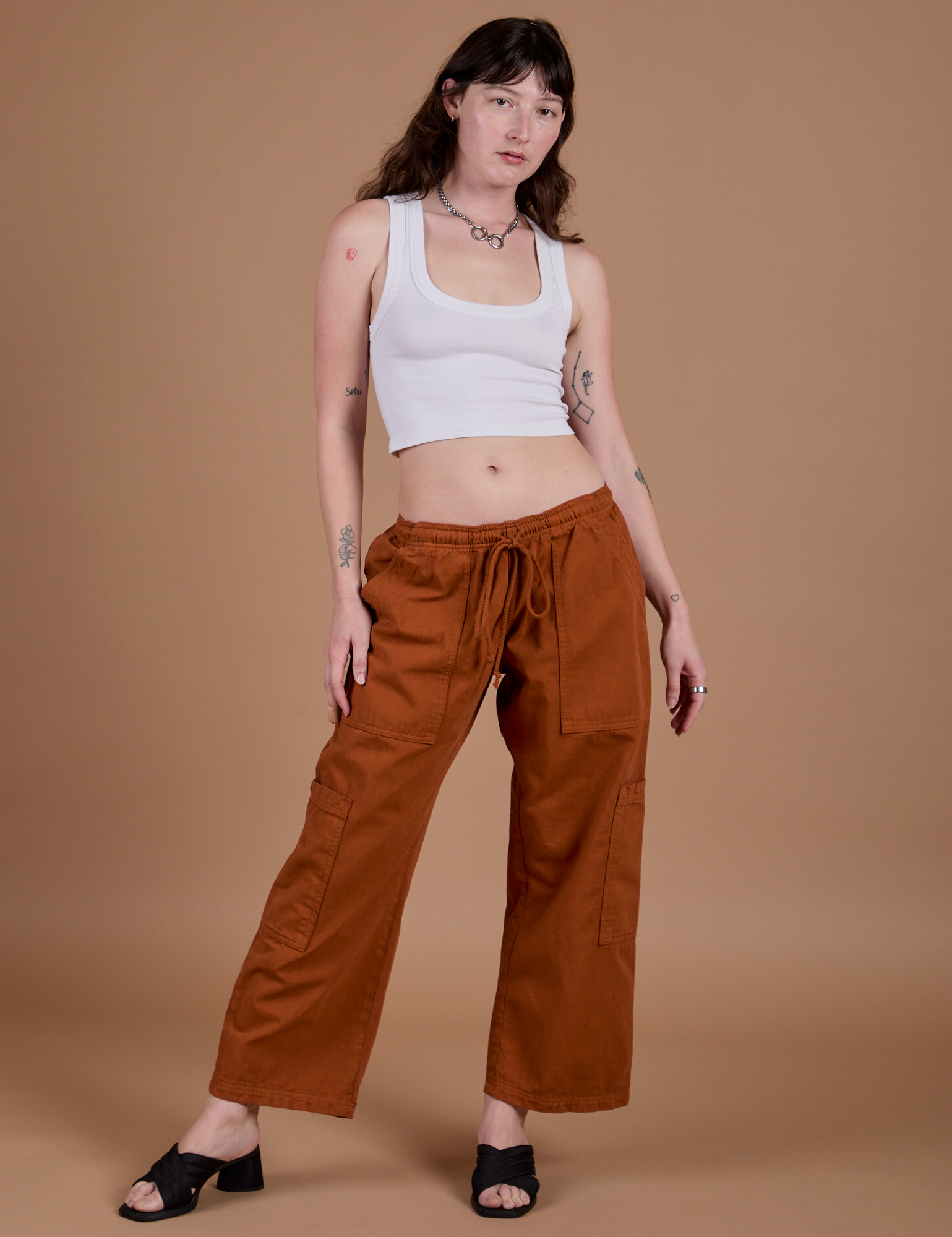 Alex is 5’8” and wearing XXS Drop Pocket Cargo Pants in Burnt Terracotta paired with a vintage tee white Cropped Tank
