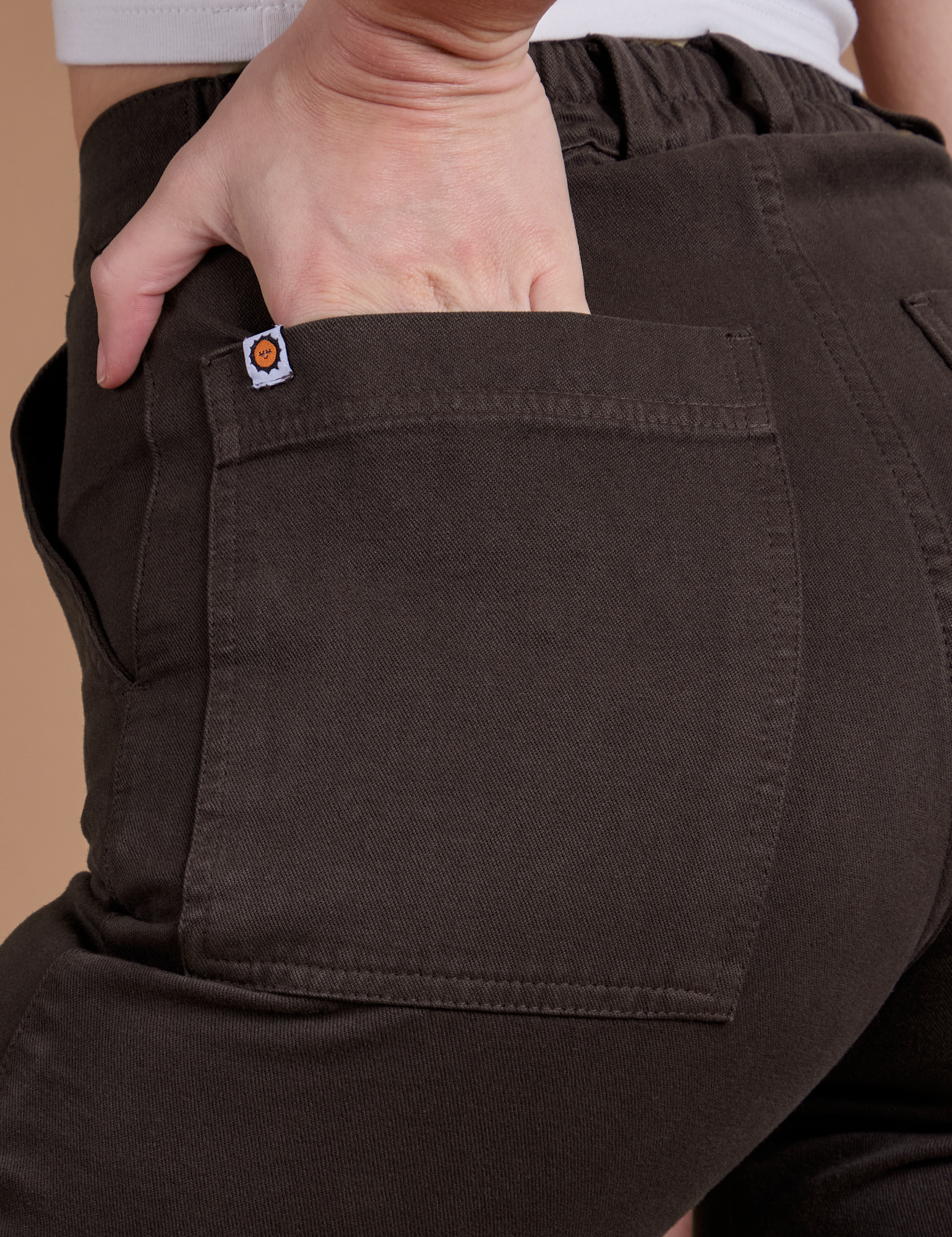 Close up of Alex's hand in the back pocket of Organic Work Pants in Espresso Brown