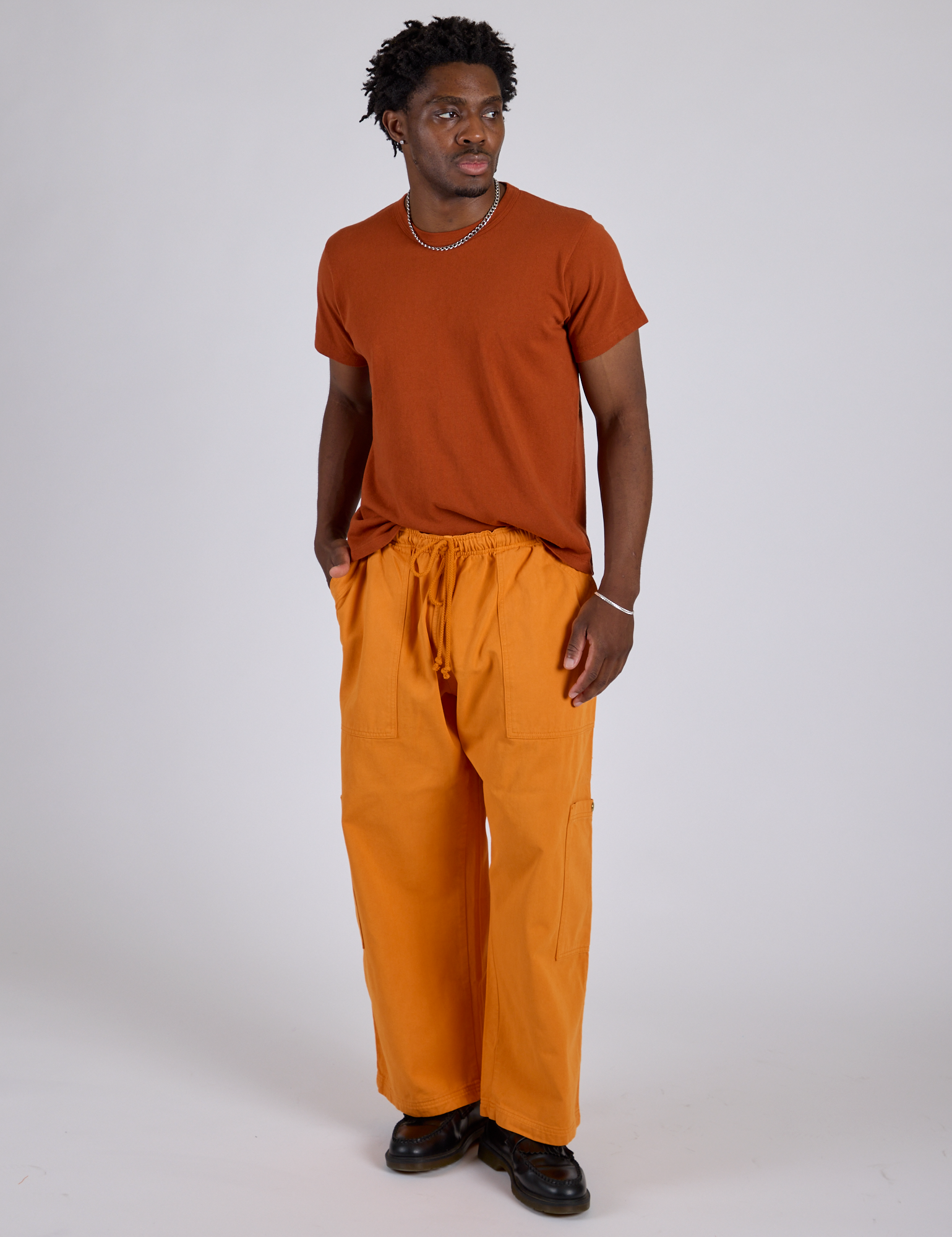 Isaac is 5’10” and wearing M Drop Pocket Cargo Pants in Creamsicle Orange paired with a burnt terracotta Organic Vintage Tee