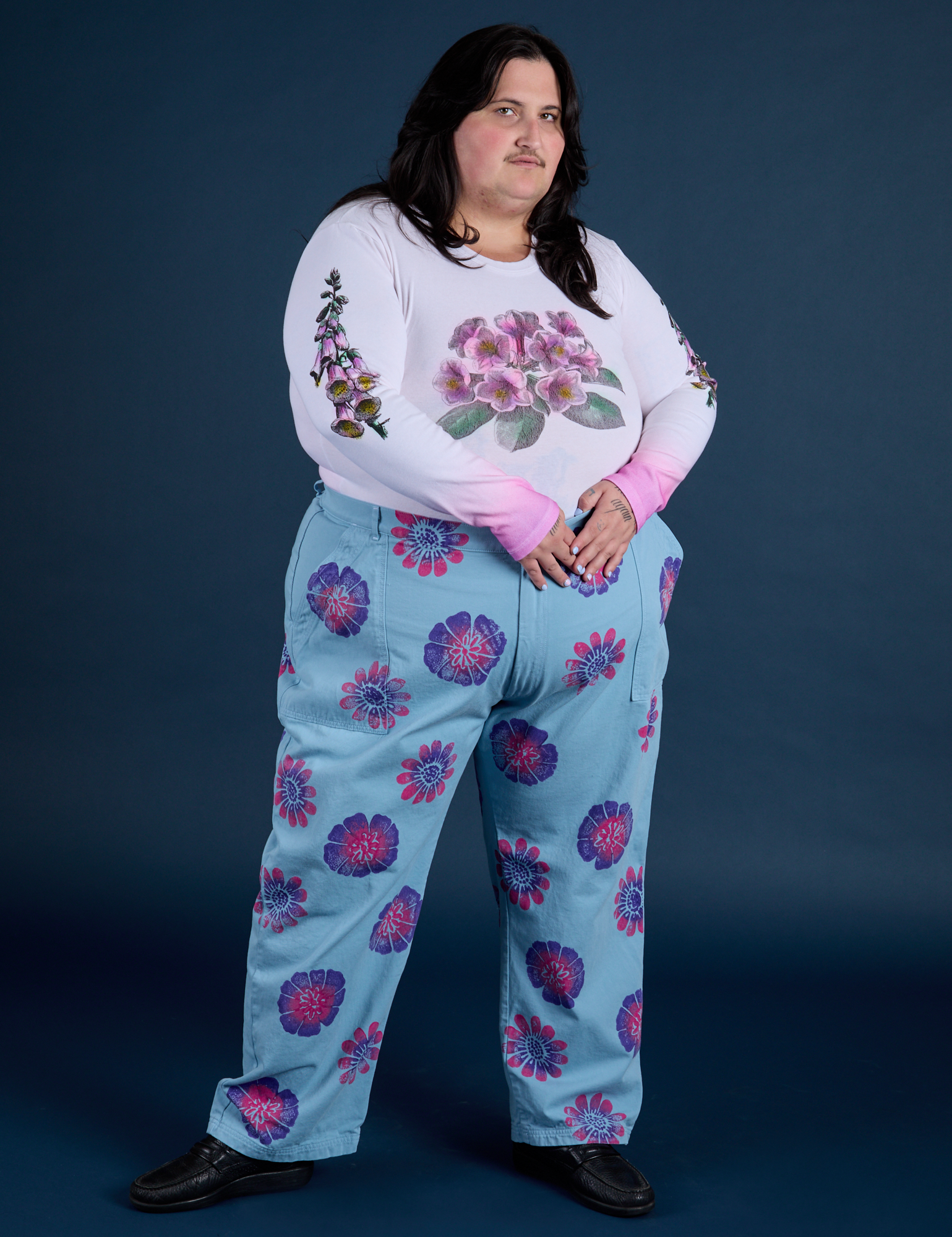 Sam is wearing Floral Painted Work Pants in Blue and Floral Long Sleeve Baby Tee in pink