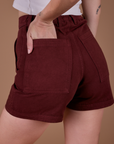 Close up of Alex's hand in the back pocket of Classic Work Shorts in Red Wine