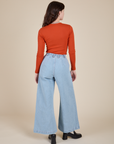 Back view of Long Sleeve Baby Tee in Chili Red and light wash Indigo Wide Leg Trousers on Alex