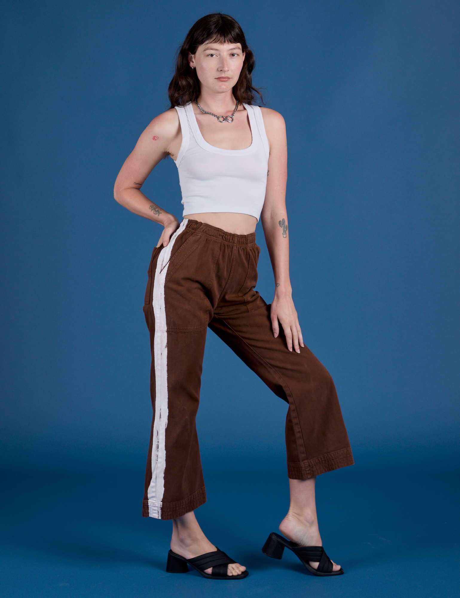 Angled front view of Painted Action Pants in Fudgesicle Brown and Cropped Tank in Vintage Tee White on Alex