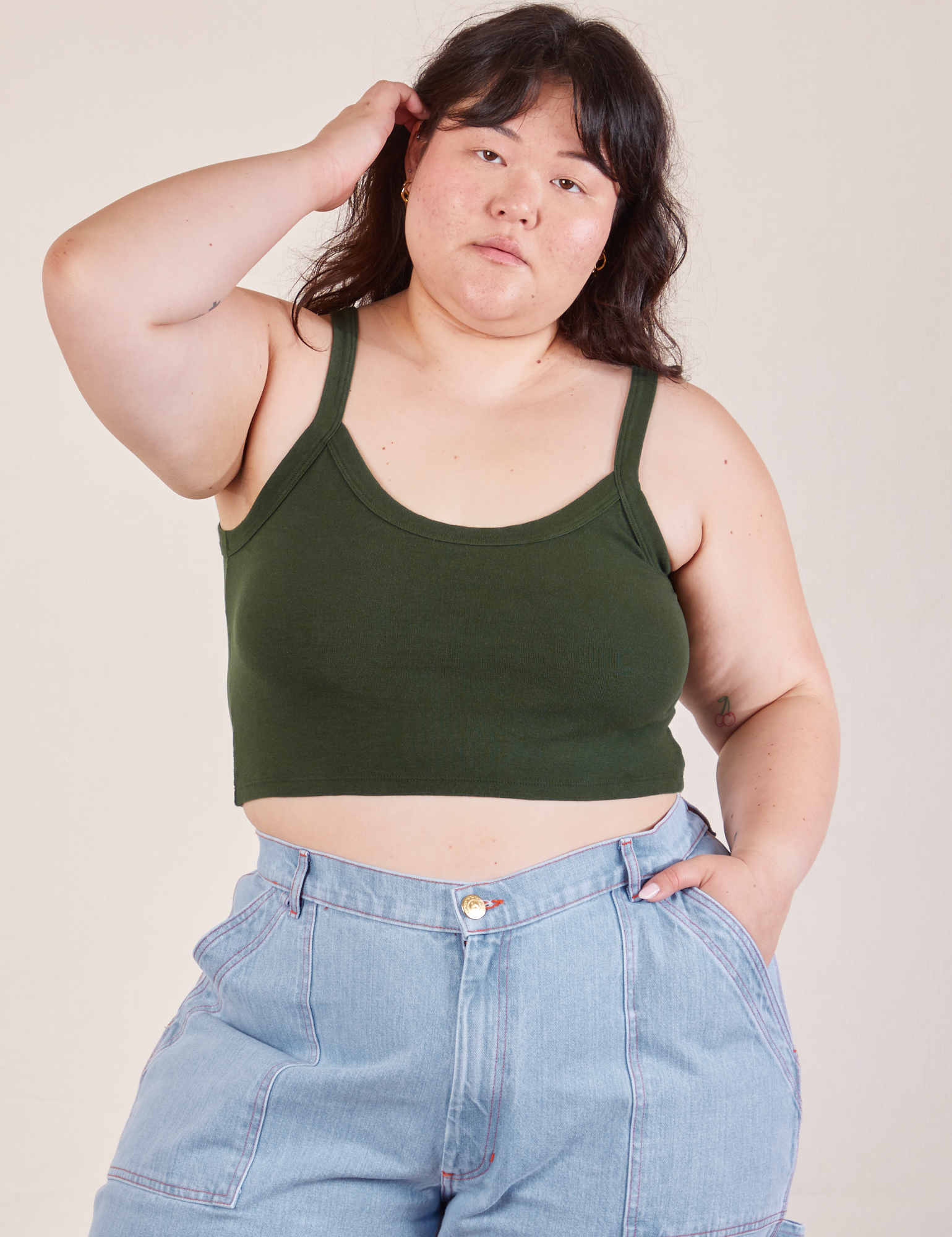 Ashley is 5’7” and wearing L Cropped Cami in Swamp Green paired with light wash Carpenter Jeans